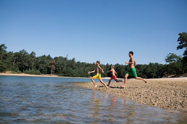 Vader rent met beide zoons het water in van de zwemplas.
