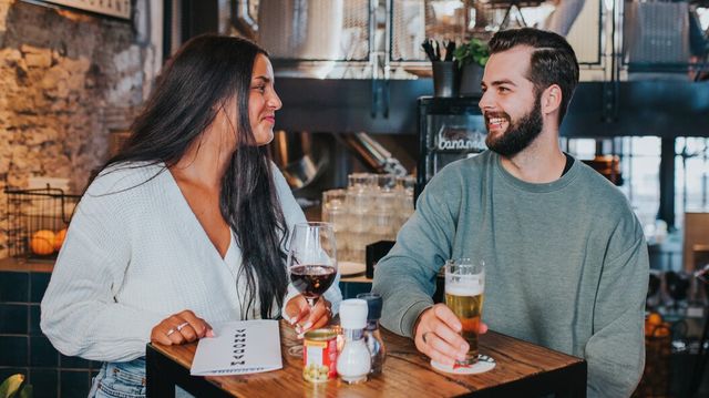 man en vrouw lachend aan tafeltje met wijn en bier