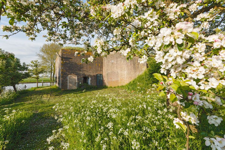 Een oud bakstenen fort omgeven door bloesem.