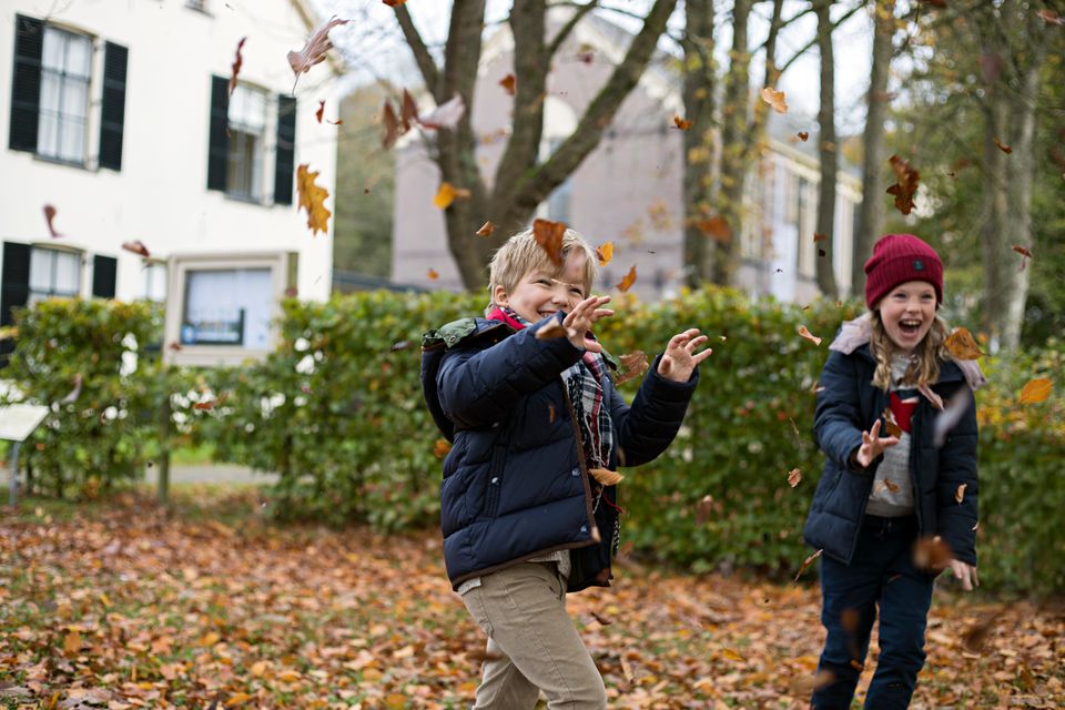 Een jongen en meisje gooien bladeren in de lucht