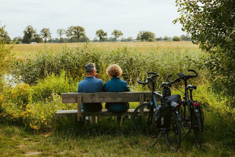 Man en vrouw zitten op het bankje kijkend naar het uitzicht van de natuur in het Land van Peel