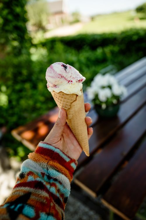 Een arm van een persoon met een schepijsje in de hand.