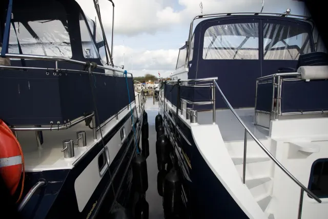Een doorkijkje tussen twee motorjachten in het water bij Yachtcharter Wetterwille in Terherne.