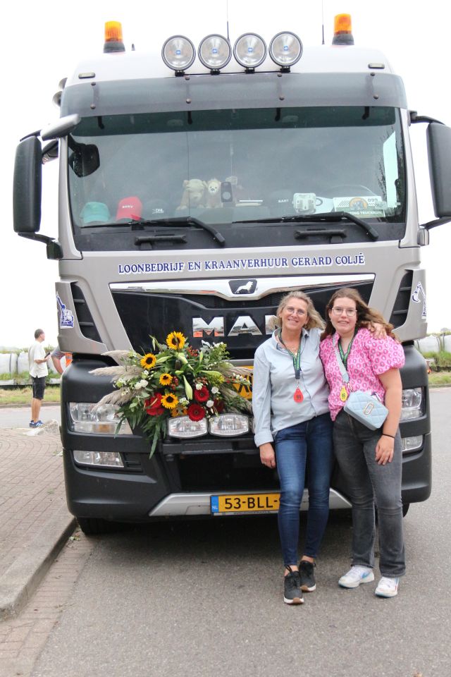 Twee deelnemers poseren voor een versierde MAN-vrachtwagen tijdens de Truckrun Groene Hart.