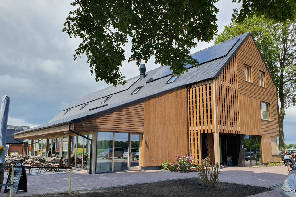 Een hotel met houten buitenkant met terras ervoor.