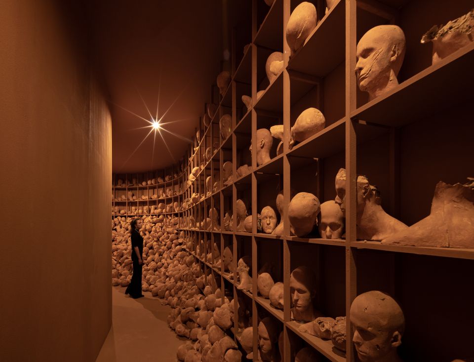 Bezoeker in installatie vol keramieken koppen in tentoonstelling Levi van Veluw in Singer Laren.