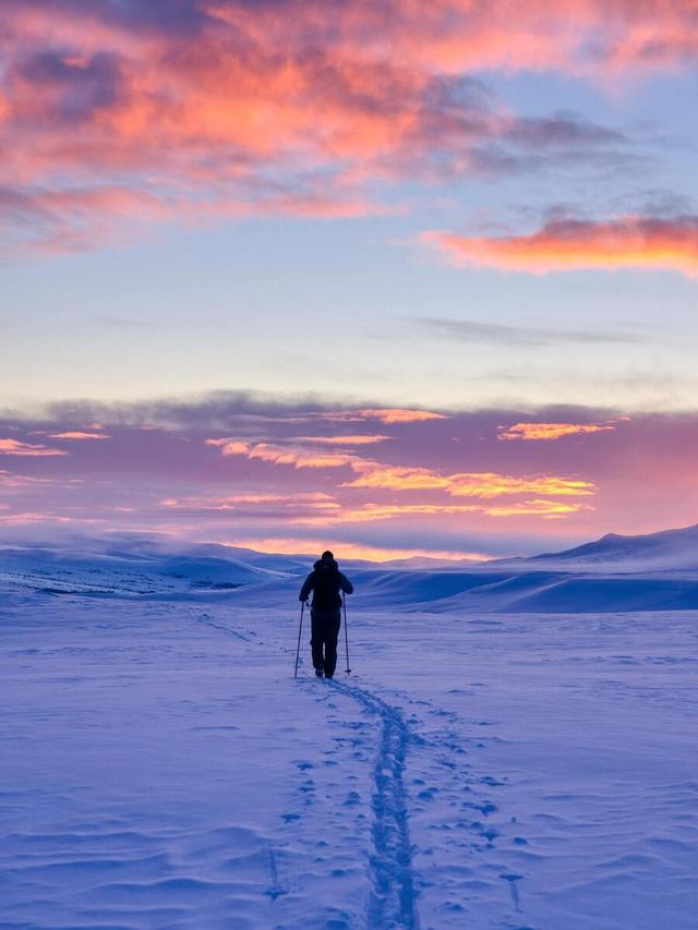 Image of a person hiking in the snow during a beautiful sunset
