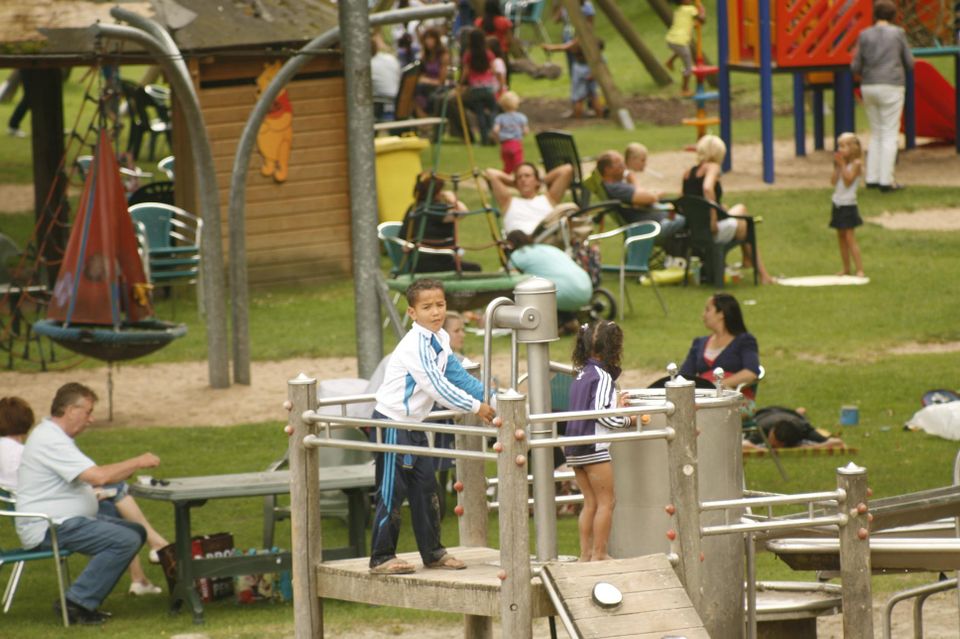 Kinderen zijn aan het spelen in een speeltuin op alle speeltoestellen.