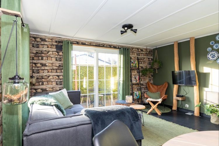 Groen met grijs, knus ingerichte woonkamer met openslaande deuren naar een tuin.