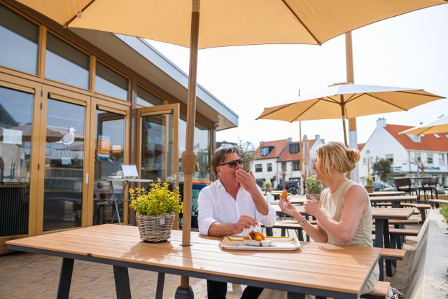 Echtpaar geniet van verse kibbeling bij Vis an Zae op het Andreasplein in Katwijk aan Zee.