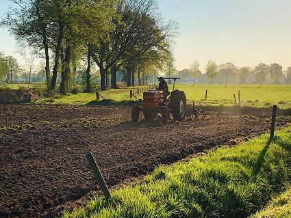 Een tractor rijdt op een stuk landbouwgrond