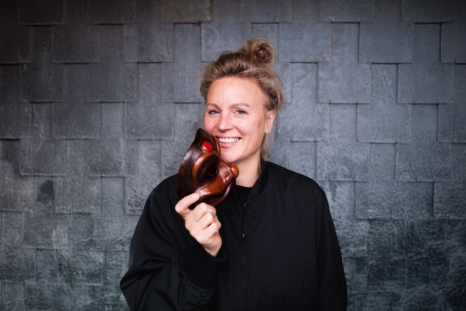 Theatervoorstelling Harlekino van Katrien van Beurden in Het Klooster Woerden, Groene Hart, met portret van de theatermaker die lachend een bruin theatermasker vasthoudt.