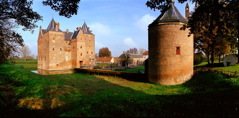 Een kasteel omgeven door groen tegen de ondergaande zon.