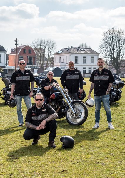Groep Harley-Davidson-rijders poseert met motoren op het Exercitieveld in Woerden tijdens Harleydag, gekleed in bijpassende clubkleding en met motorhelmen.