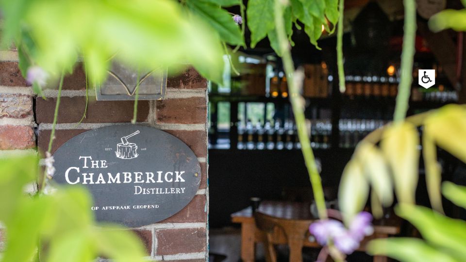 Entree van The Chamberick Distillery in Kamerik, ambachtelijke distilleerderij met proefruimte en flessen op de achtergrond.