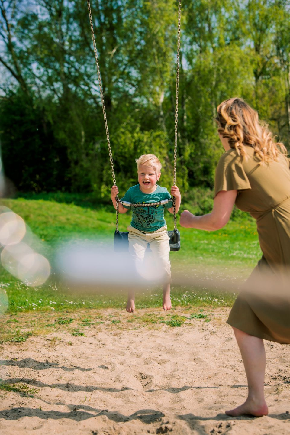 Jongen zit lachend een schommel