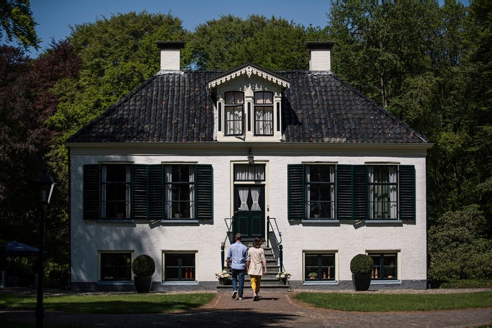 Een stel loopt op een zonnige dag over een pad richting huis Westerbeek in Frederiksoord.