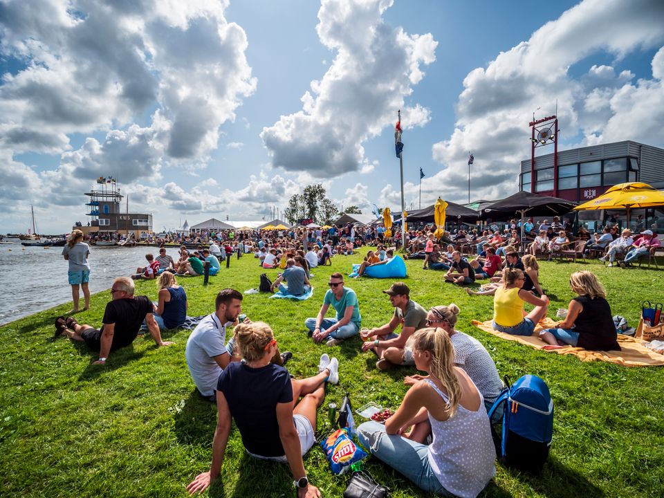 mensen zitten op een grasveld bij het sneekermeer