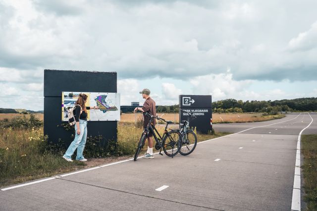 Een stel kijkt op de borden met informatie  over Park Vliegbasis Soesterberg. Een oude landingsbaan waar je nu overheen kan fietsen.