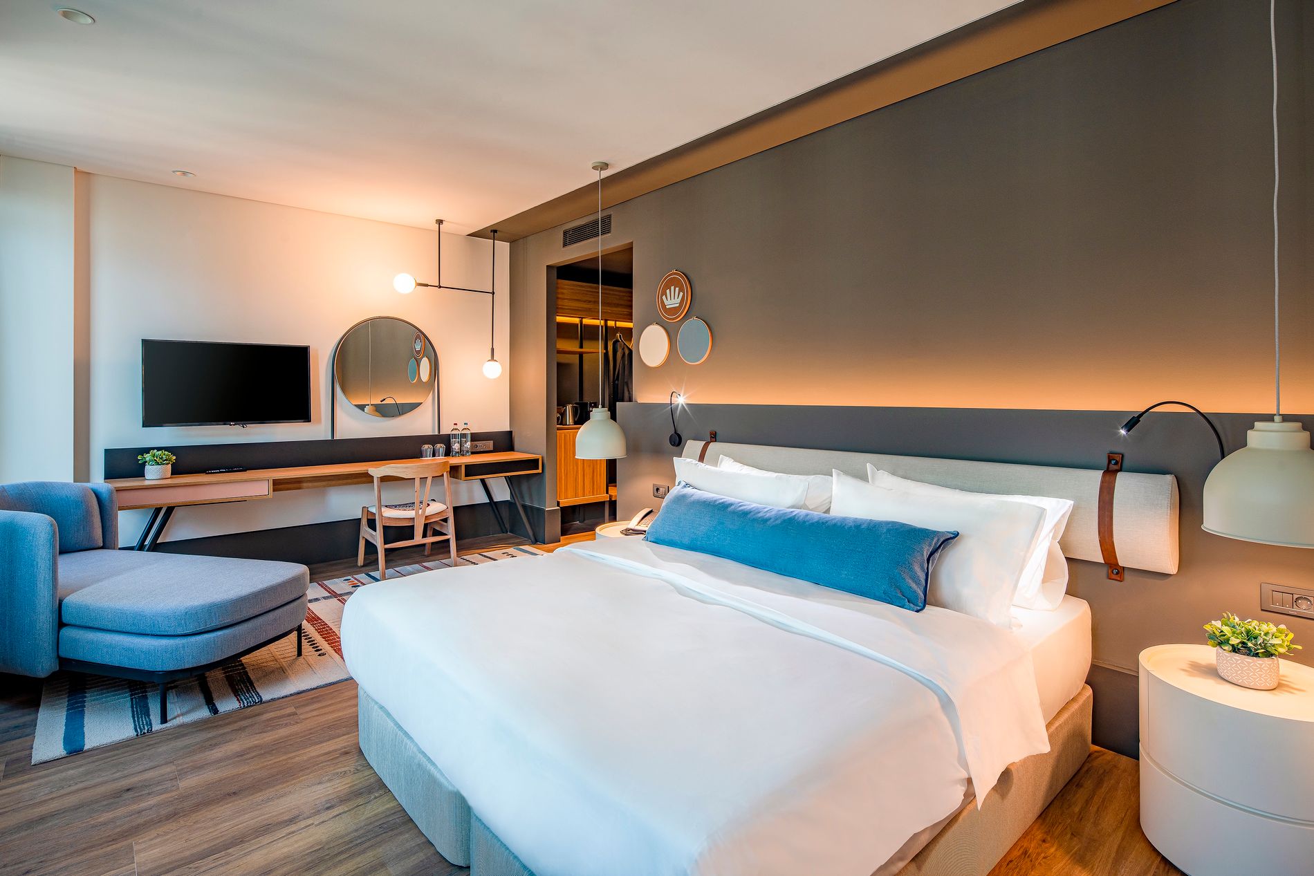 Foto van een moderne hotelkamer met groot bed in het midden, witte lakens en blauwe accenten.