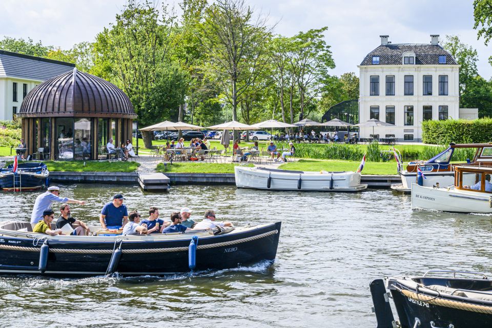 Bootjes varen op de Vecht langs het terras en theehuis van hotel Flora Batava.