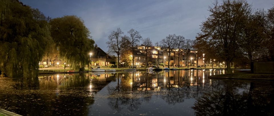 Tijdens een avondwandeling langs het water in Woerden weerspiegelen de stadslichten in de rustige singel. De bomen, boten en karakteristieke bebouwing zorgen samen voor een kalme en warme avondsfeer.