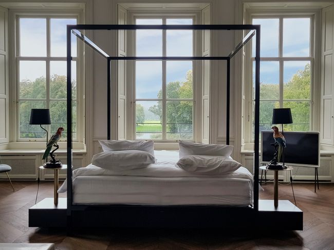 De Grand Suite in Parc Broekhuizen met een bed dat uitkijkt op de Kasteeltuinen