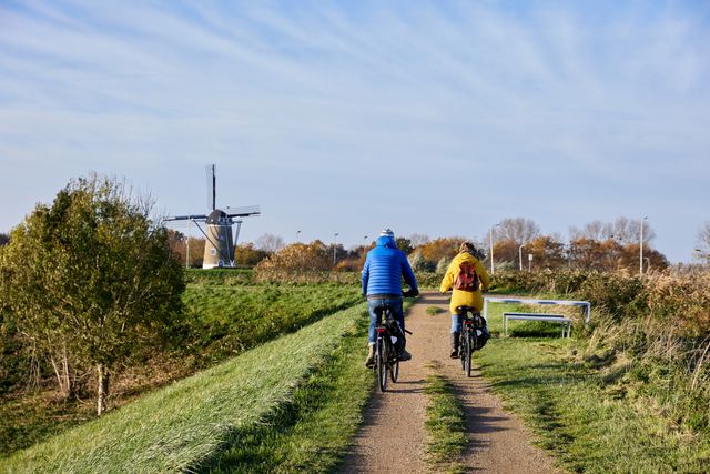 Fietsers over dijk met molen op achtergrond