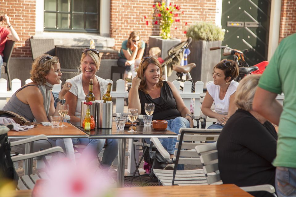 Horecaterras in Woerden, Groene Hart, met bezoekers die genieten van een drankje op een zonnig terras in de historische binnenstad, gezellige sfeer voor een dagje uit, lunch of borrel.