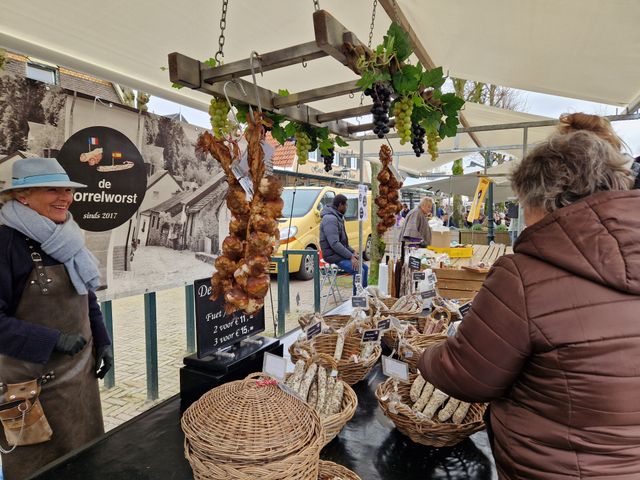 Verschillende mensen bij een worstenkraampje op de Wintermarkt in Balk.