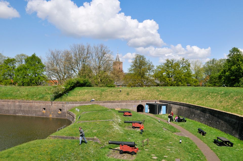 Kindje rent over de vestingwal tussen de rode kanonnen van het Nederlands Vestingmuseum door.