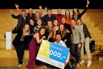 Prijsuitreiking Cultuurprijs Woerden in Woerden, Groene Hart. Groepsfoto van de winnaars en betrokkenen op het podium met een cheque van € 3.000 en de Cultuurprijs Woerden na de feestelijke uitreiking.