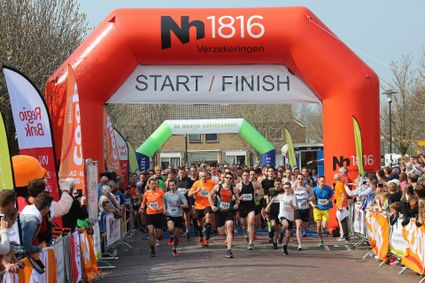 Hardloopevenement Rondje Zegveld met een grote groep deelnemers bij de start onder de start- en finishboog in Zegveld, gemeente Woerden, in het Groene Hart tijdens een sportief dorps evenement