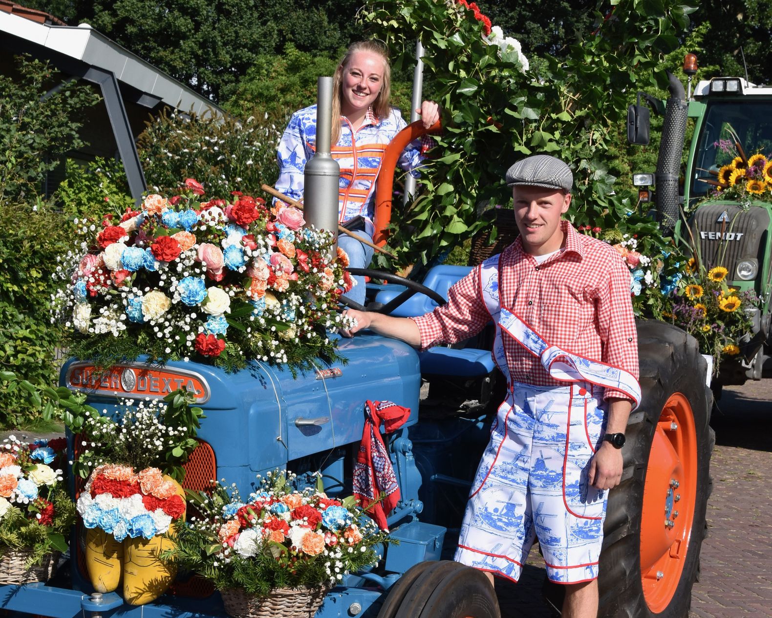 Man en vrouw op tractor die versierd is met bloemen