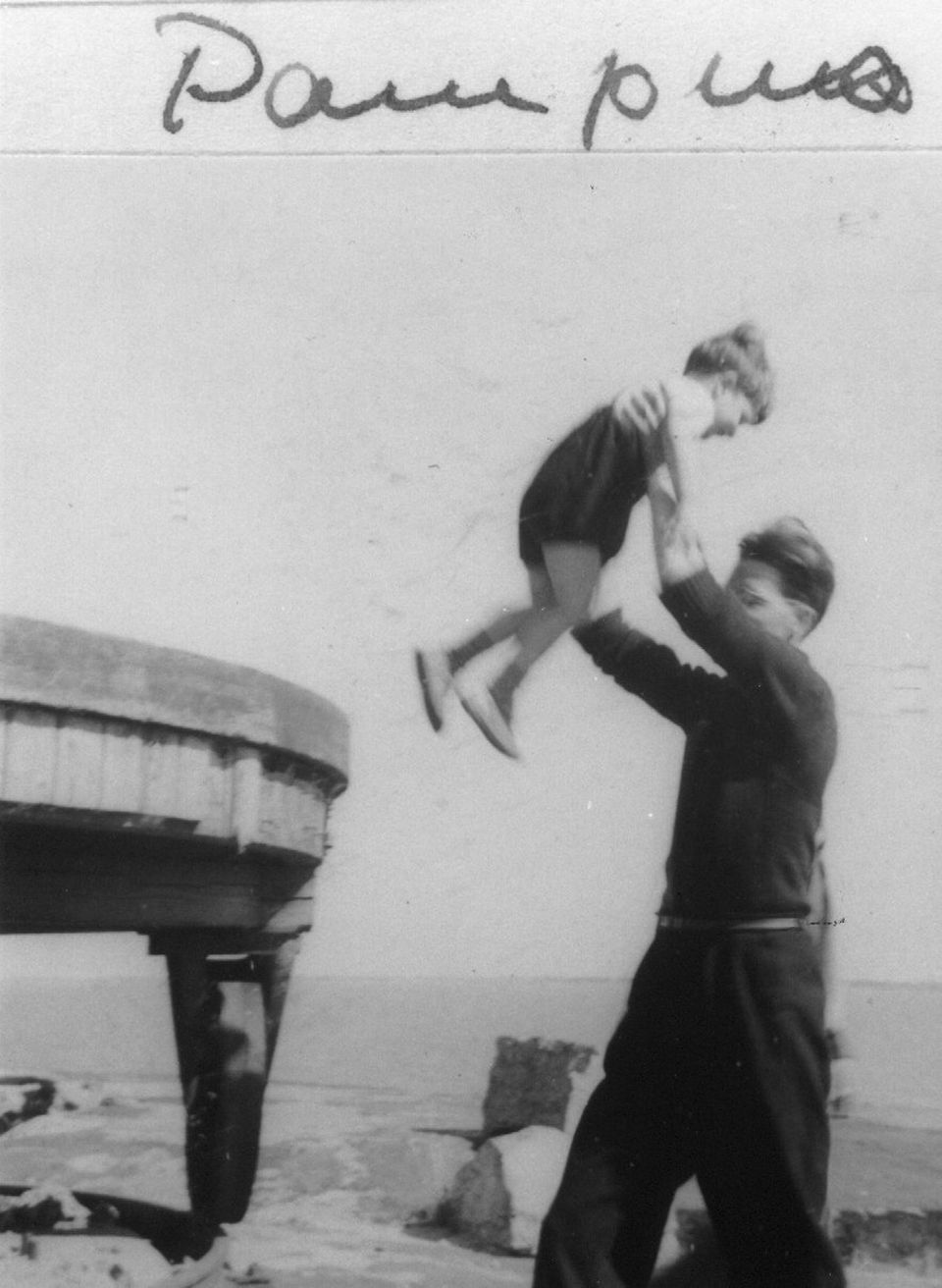 Zwart-wit Foto vlak na WWII, een vader tilt zijn zoon in de lucht op Pampus