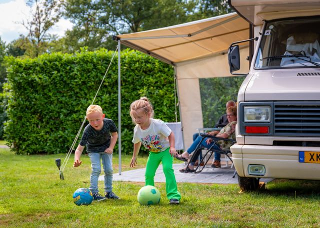 Twee kinderen spelen voor de caravan van opa en oma op camping le silence
