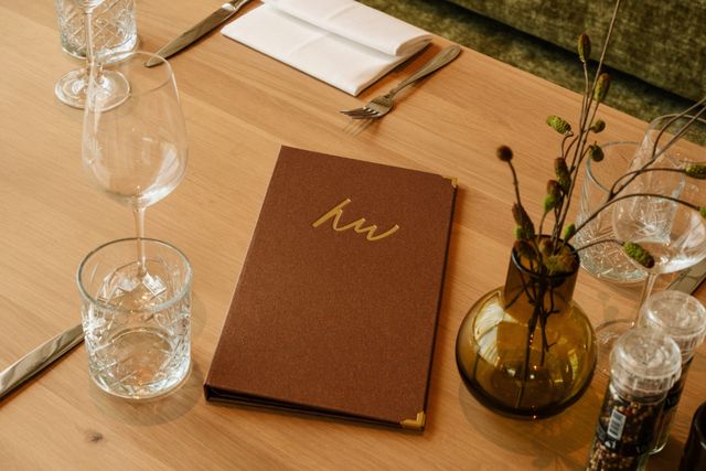 Hotel Van der Valk Woerden, Woerden, Groene Hart, menukaart op een gedekte tafel met glazen, bestek en tafeldecoratie in een eigentijds restaurant.