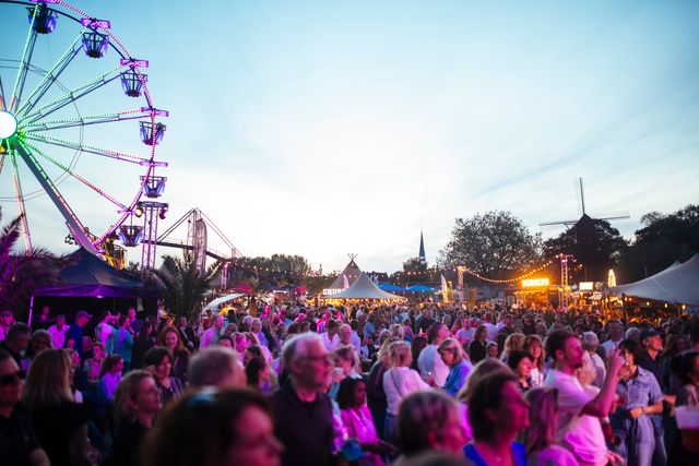 Bezoekers genieten van een zomers festival in het Groene Hart met foodtrucks, een reuzenrad, live muziek en sfeervolle verlichting tijdens een warme zomeravond.