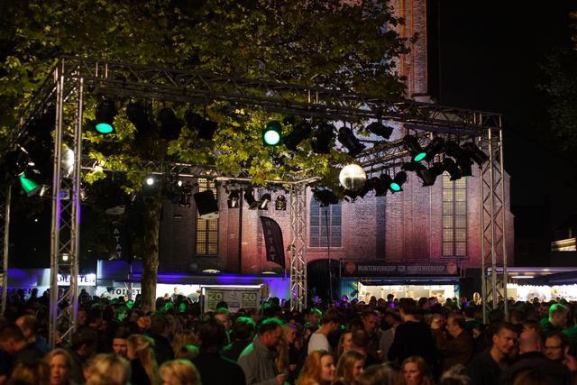 Drukke en sfeervolle Nacht van Woerden met feestverlichting, volle dansvloer en de Petruskerk op de achtergrond in het centrum van Woerden.