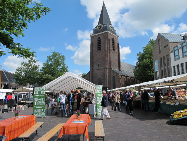 Streekmarkt in Woerden met kramen en bezoekers op het Kerkplein bij de Petruskerk.