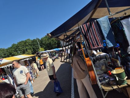 Markt op een zonnige dag met gekleurde kramen en mensen die aan het kijken zijn.