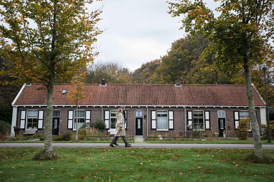 Een man en vrouw lopen voor de koloniehuizen in Veenhuizen langs.