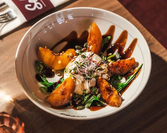 Salde met burata en perziken met saus erover heen