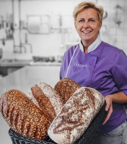 Bakker staat glimlachend met een grote mand met broden erin.