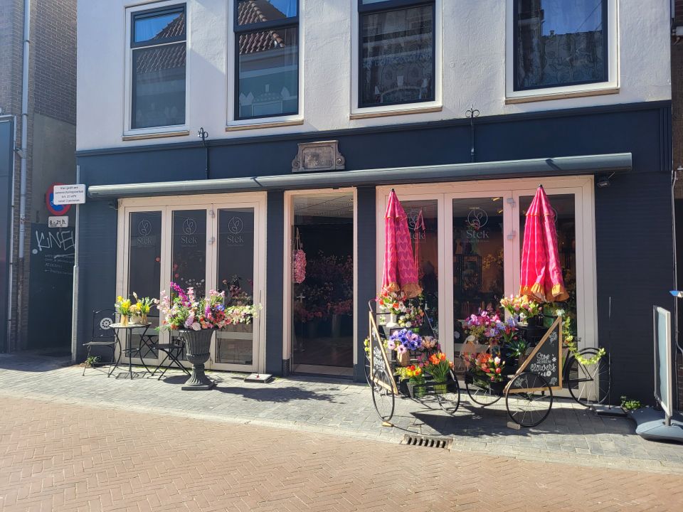 Bloemenwinkel Bloemenwinkel Stek in Woerden, Groene Hart, gevel van de bloemenwinkel met kleurrijke boeketten, bloementafels en decoratieve bloemenkarren buiten in het centrum.