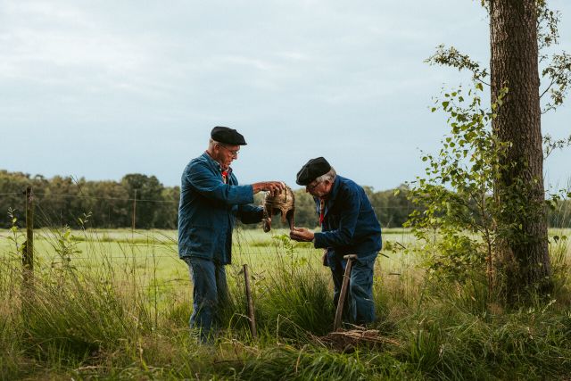Twee mannen die een helm bewonderen in de natuur