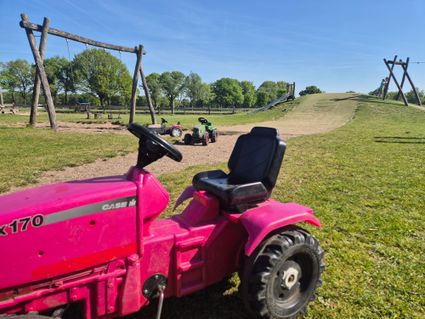 Speelgoedtraktor op buitenterrein met speelplaats bij De Gerrithoeve
