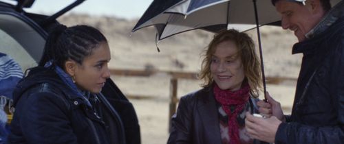 Een man en twee vrouwen die onder paraplu's staan