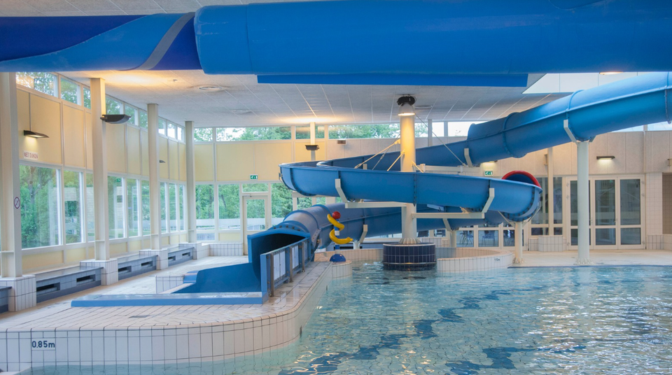 Zwembad Batenstein Woerden, provincie Utrecht, Groene Hart, modern overdekt recreatiebad met grote blauwe waterglijbaan, peuterbad en helder zwemwater voor een gezinsuitje.