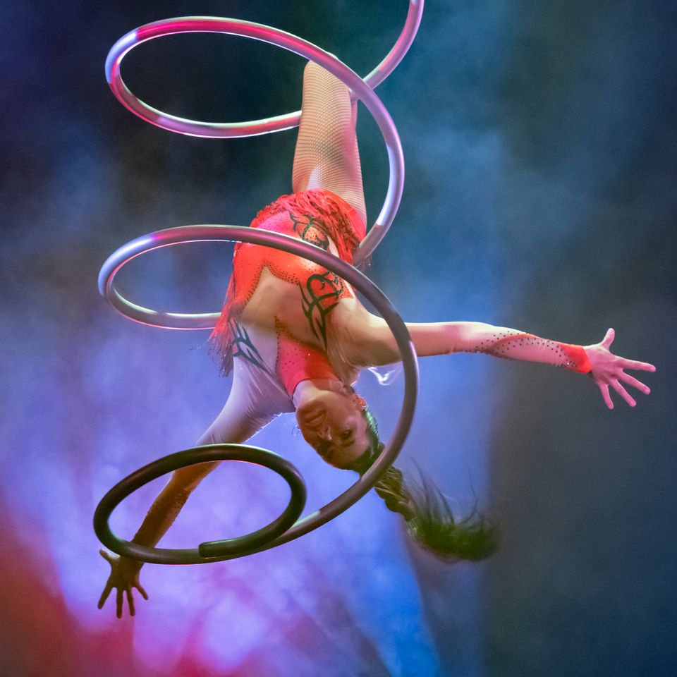 Een vrouw die op haar kopt hangt in het circus